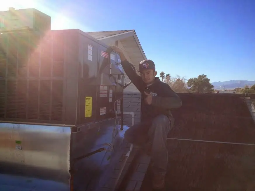 HVAC technician performing AC Tune-Up on a rooftop unit in Parlier